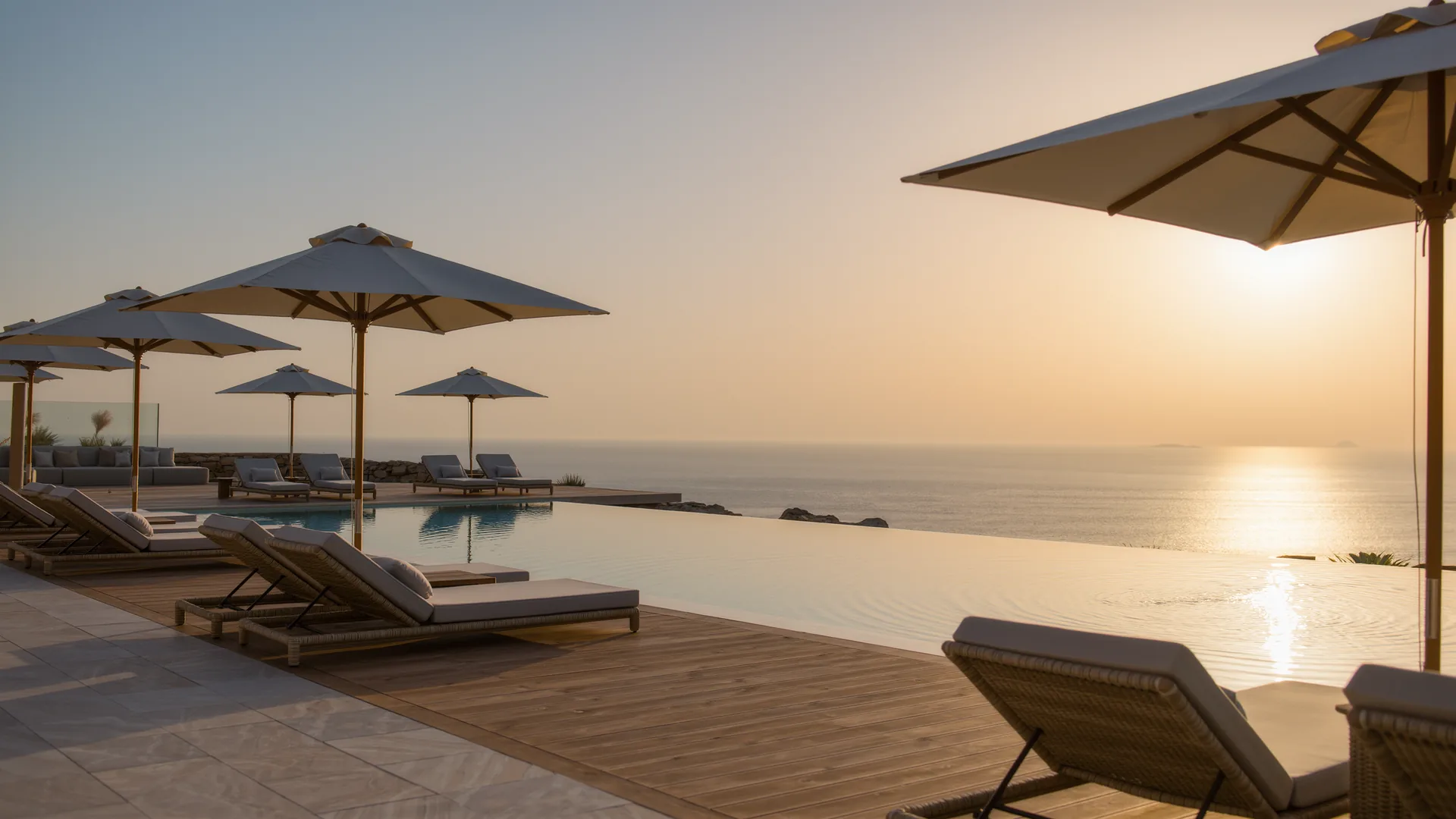 Resort pool terrace with parasols overlooking the sea at sunset