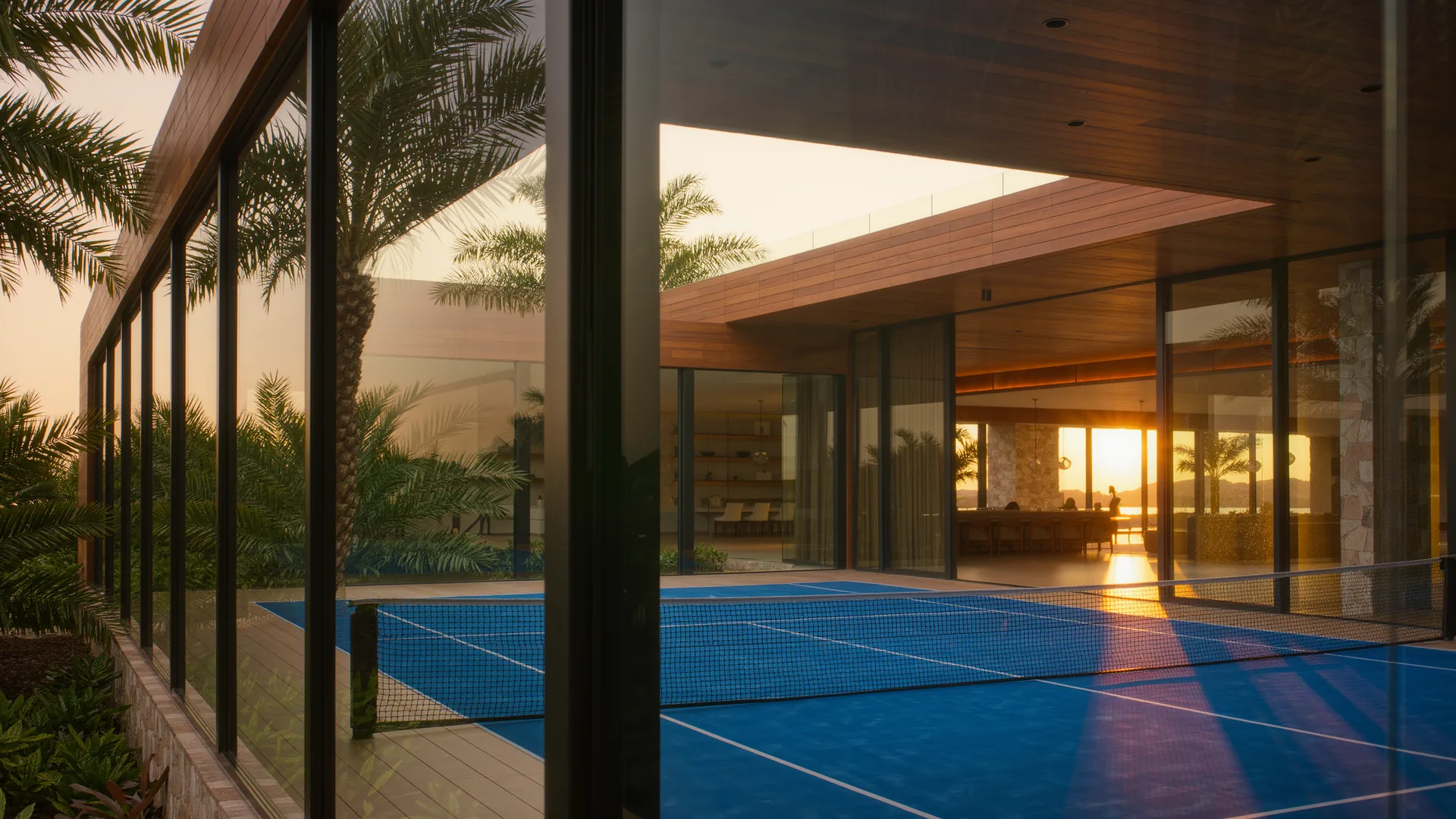 Padel court with glass walls and a blue surface among palm trees
