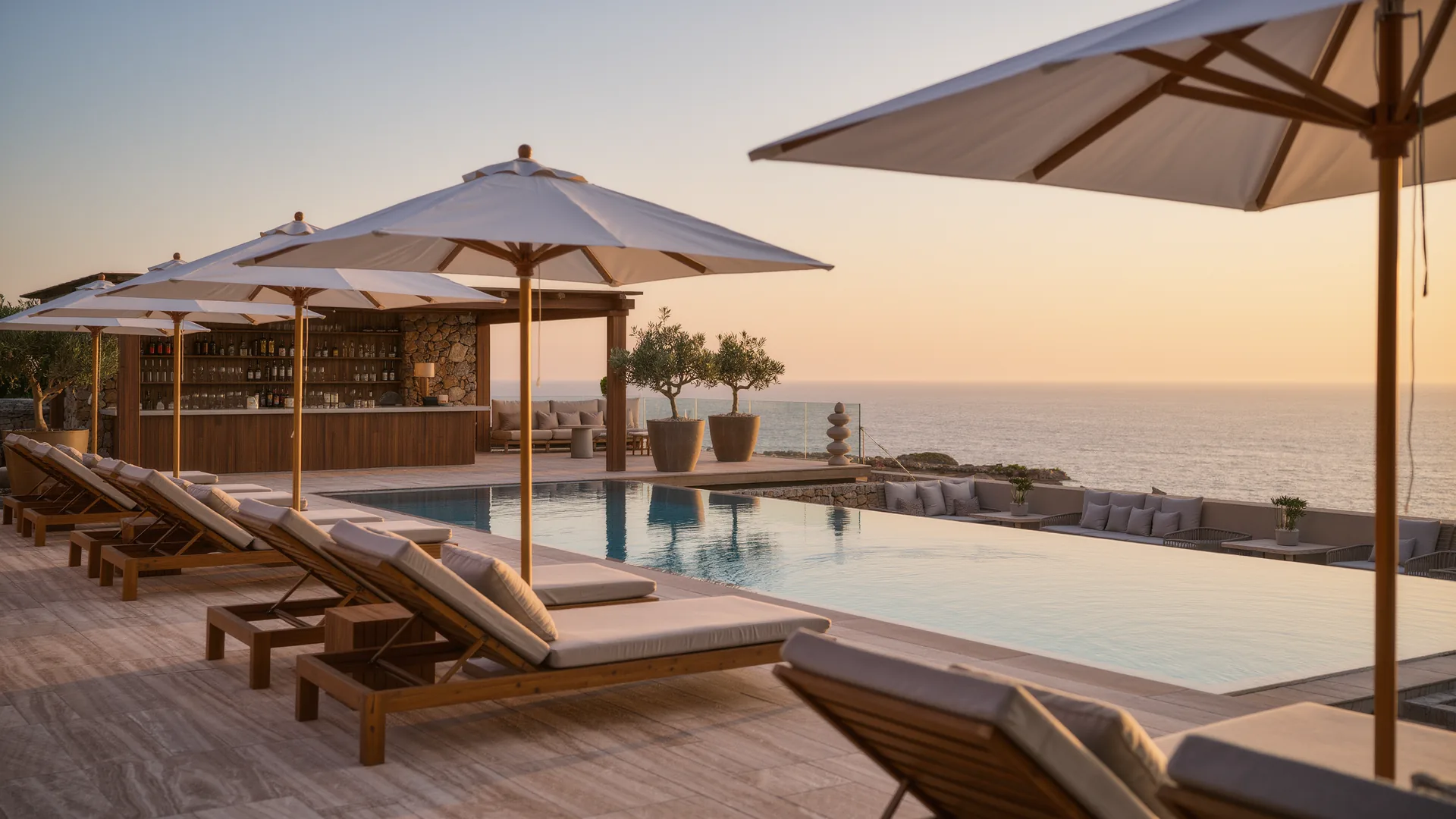 Resort pool terrace with parasols overlooking the sea at sunset