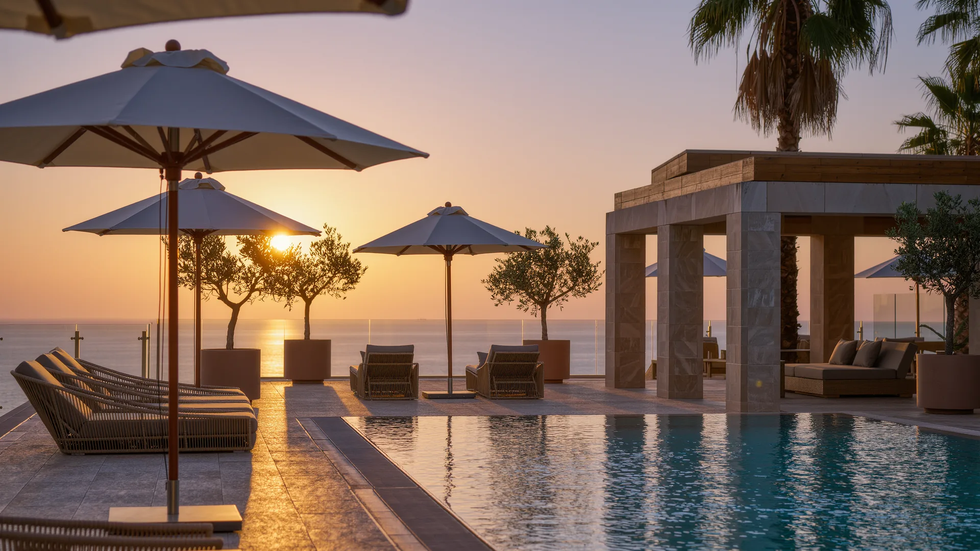 Resort pool terrace with parasols overlooking the sea at sunset