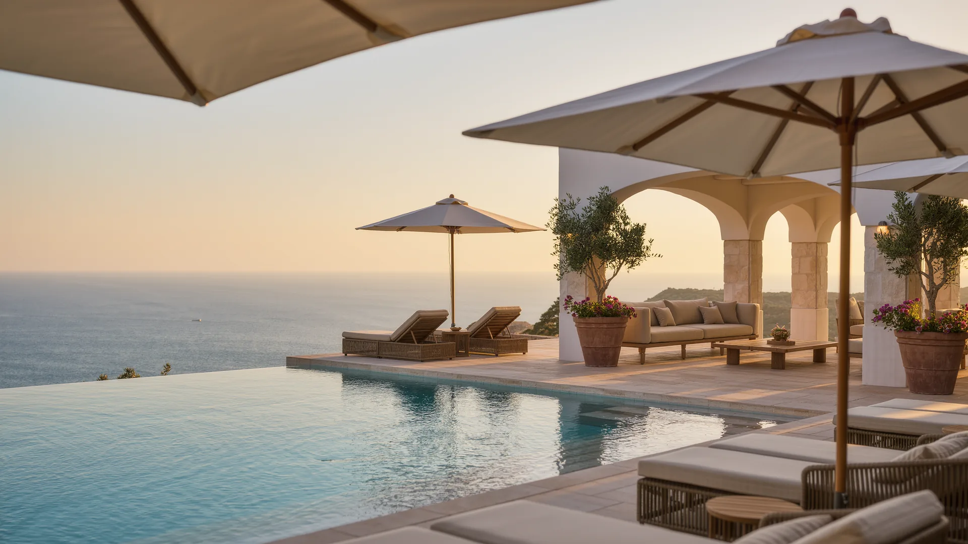 Resort pool terrace with parasols overlooking the sea at sunset