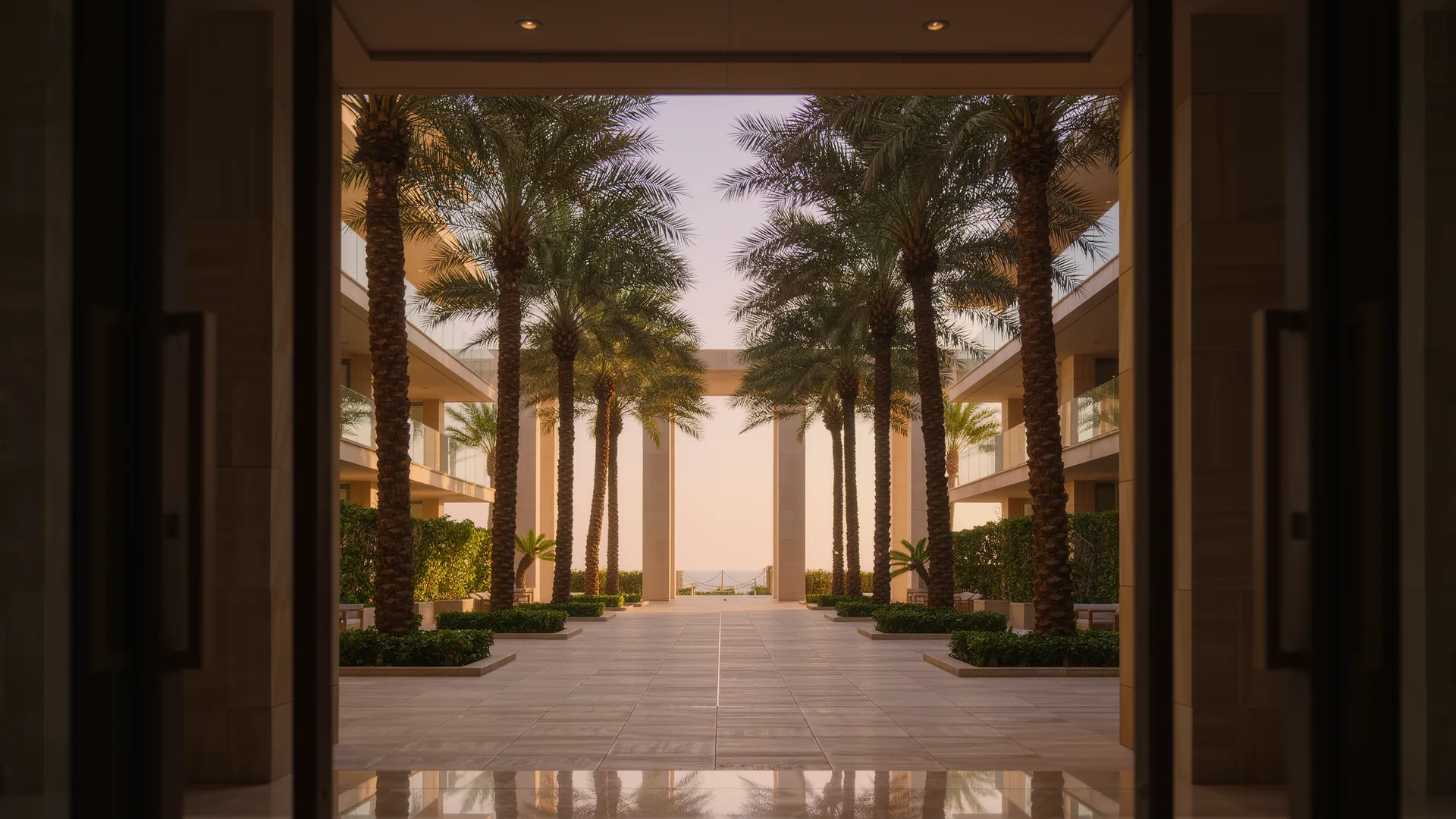 Apartment building courtyard with palms and a clean tiled walkway in morning light