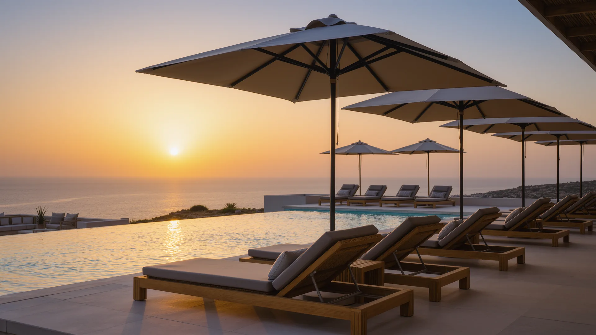 Resort pool terrace with parasols overlooking the sea at sunset